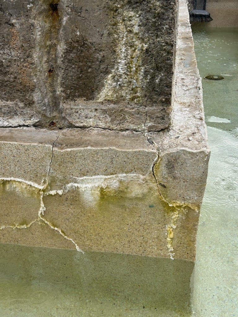 Structural cracks and calcium deposits on spa wall indicating active leak — Dripping Springs