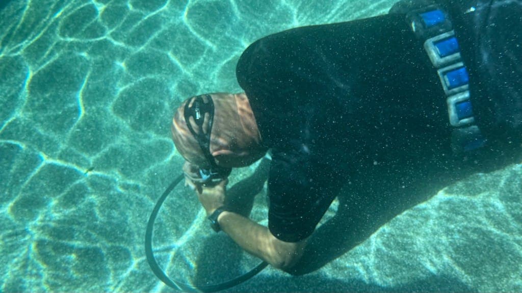 Diver with hydrophone inspecting pool floor during underwater leak detection — Liberty Hill